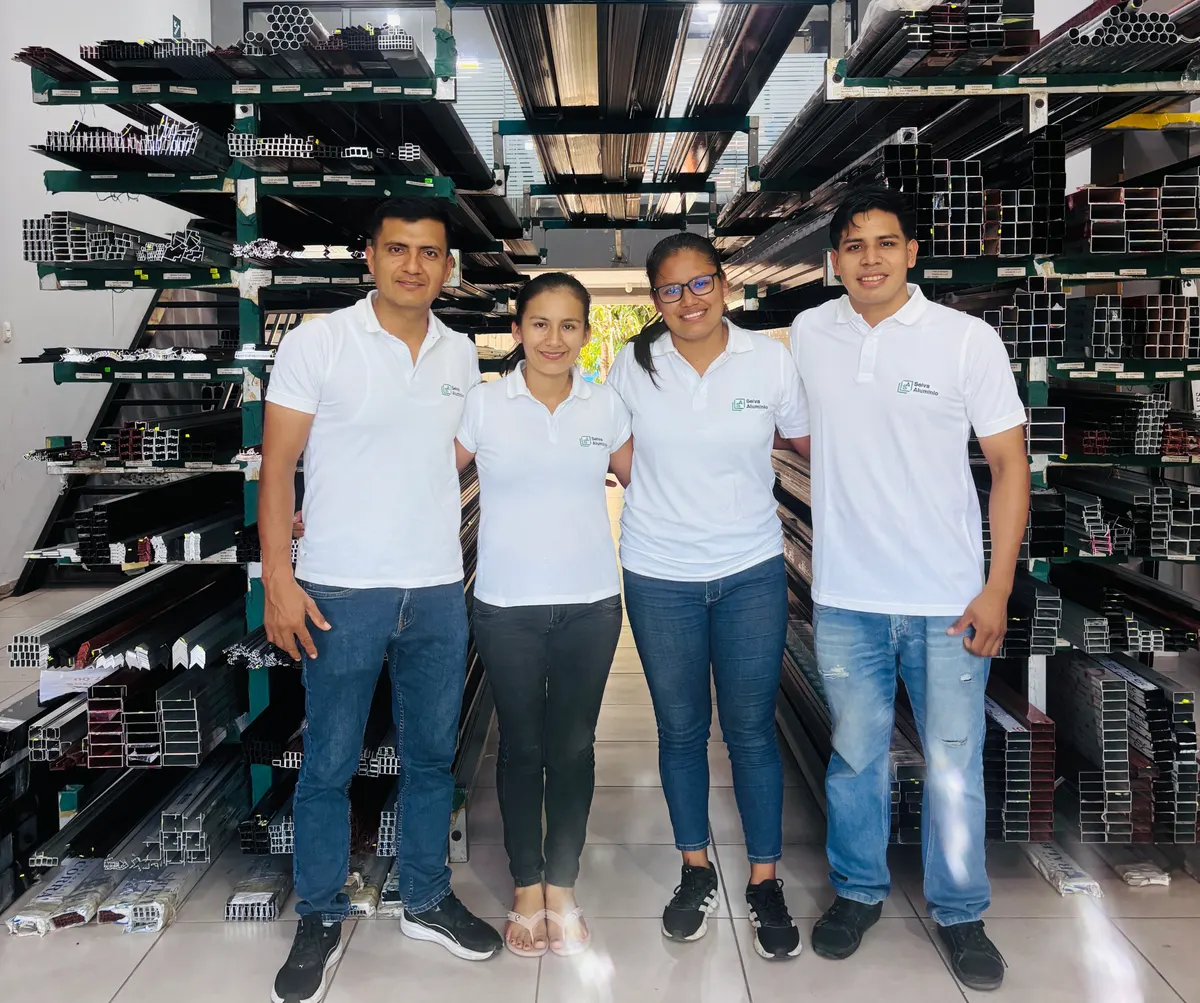 El equipo de Selva Aluminio en la tienda, entre racks de perfiles de aluminio