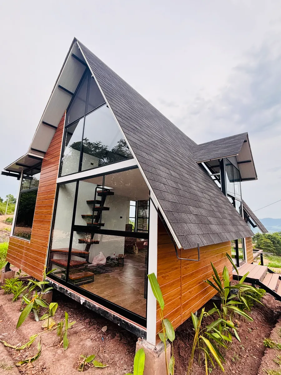 Cabaña estilo A-frame con ventanales de aluminio negro y vidrio